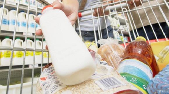 Couple in supermarket, woman putting milk in trolley, low angle view